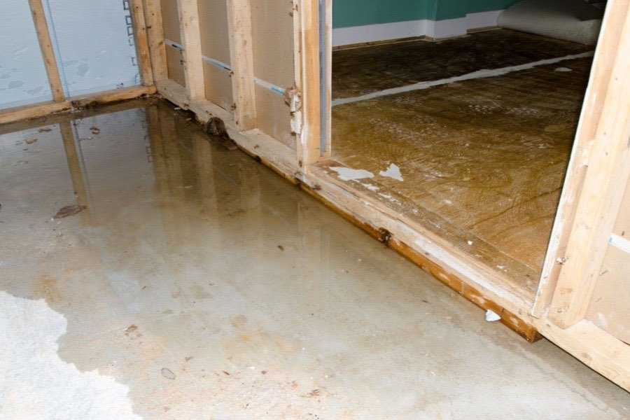 Standing water across a stripped floor after flooding in a Portland home